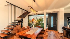 Ein moderner Essbereich mit Holztisch, gepolsterten Stühlen und einer Treppe mit Metallgeländern.