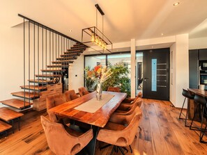 A modern dining area with a wooden table, cushioned chairs, and a staircase with metal railings. - Beautiful villa Lara in Vrana with pool by Interhome (Drage)