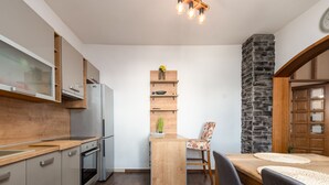 Eine kompakte Küche mit Einbauofen, Kühlschrank und einem Holzespeise Tisch mit Stühlen.