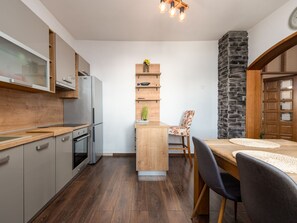 Eine kompakte Küche mit Einbauofen, Kühlschrank und einem Holzespeise Tisch mit Stühlen.
