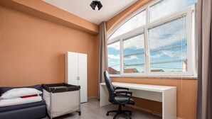 Ein Hotelzimmer mit Schreibtisch, Stuhl, Wickeltisch und Kleiderschrank.