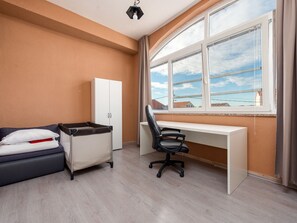 Ein Hotelzimmer mit Schreibtisch, Stuhl, Wickeltisch und Kleiderschrank.