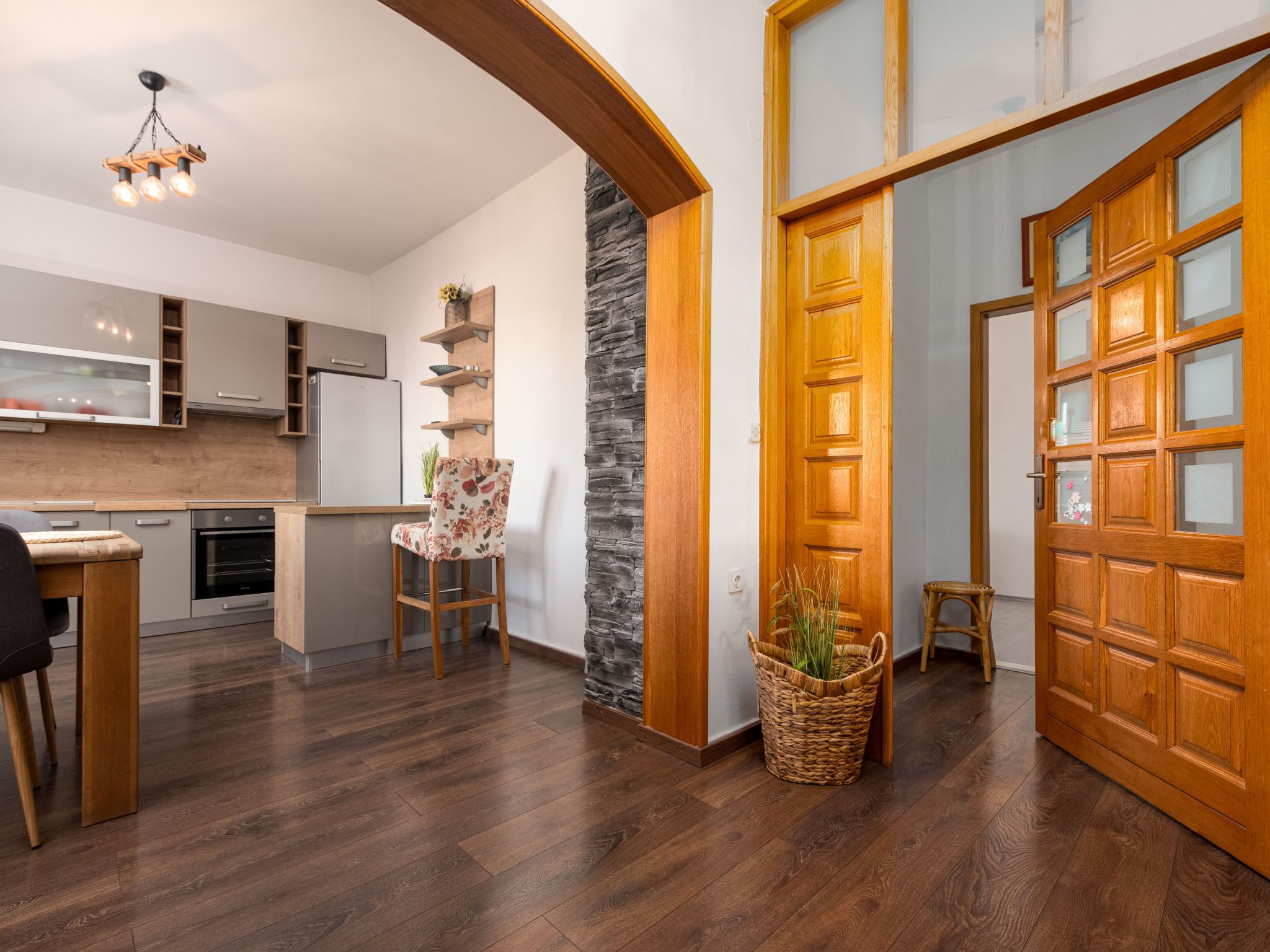A modern kitchen with a built-in fridge, wooden cabinets, and a stone accent wall.