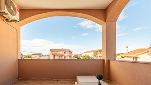 Ein Balkon mit Blick auf benachbarte Häuser, einem kleinen Tisch und einem Blumentopf.