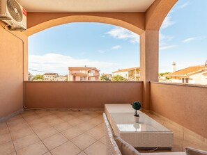 Ein Balkon mit Blick auf benachbarte Häuser, einem kleinen Tisch und einem Blumentopf.