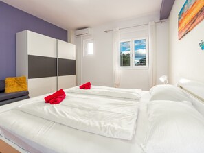 Habitación de hotel con dos camas, un armario, una ventana con vistas y un cuadro en la pared.