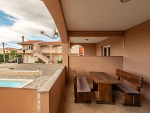 Ein Balkon mit Pool, Holzbanken und Blick auf die Nachgebäudebauten.