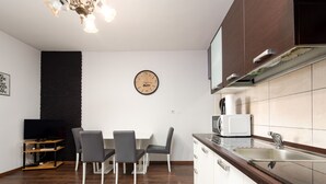 Una cocina moderna con comedor, piso de madera y un reloj en la pared.