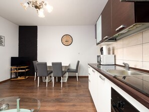 Eine moderne Küche mit Essbereich, Holzboden und einer Uhr an der Wand.