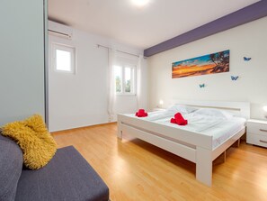 Ein modernes Schlafzimmer mit einem Bett, Nachttischen, einem Fenster und einem Bild an der Wand.