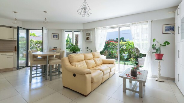 Una sala de estar moderna con sofá, mesa de comedor y zona de cocina.