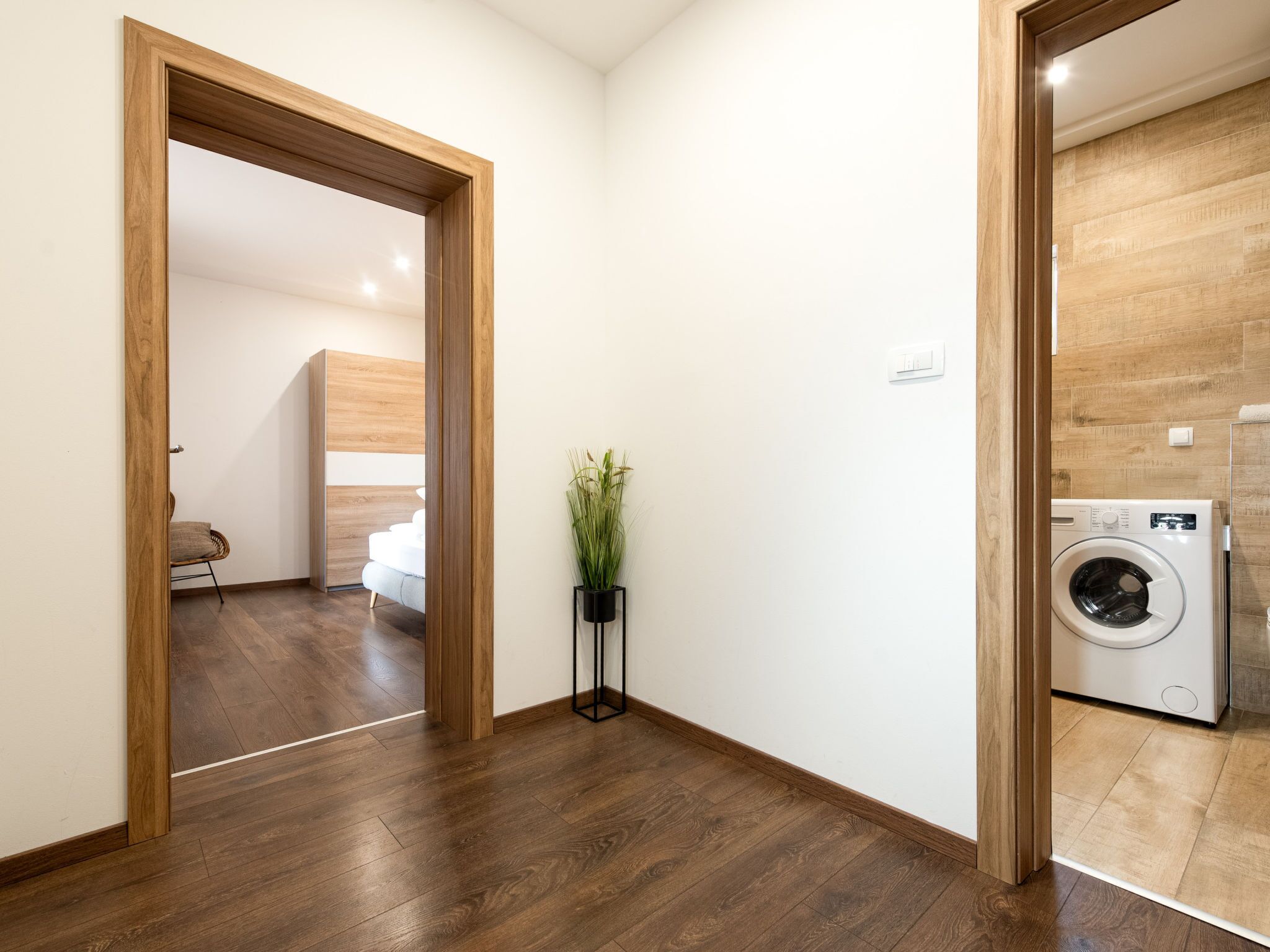 Un interior moderno con suelo de madera, lavadora y una planta.
