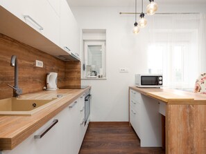 A modern kitchen with a wooden countertop, built-in oven, and a microwave. - Apartment  by Interhome (Biograd na Moru)