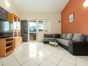 Un salon moderne avec un téléviseur à écran plat, un canapé, une table basse et un mur décoratif en pierre.