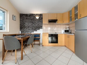Une cuisine moderne avec un mur d’accent en pierre, des armoires en bois et un coin repas avec deux chaises.