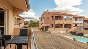 Ein Wohngebäude mit gefliestem Patio, einem Schwimmbecken und Gartenmöbeln.
