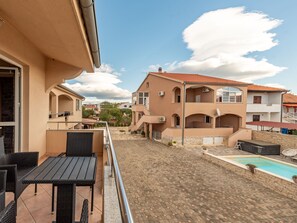 A residential building with a tiled patio, a swimming pool, and outdoor furniture. - Apartment  by Interhome (Biograd na Moru)