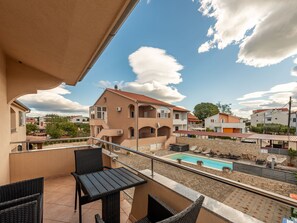 Un balcon avec une piscine, du mobilier d’extérieur et une vue sur les bâtiments voisins.