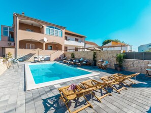 A two-story building with a swimming pool, sun loungers, and a stone wall. - Apartment Julia A2, 2+2 by Interhome (Biograd na Moru)