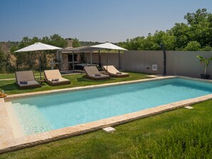 A swimming pool with lounge chairs and umbrellas, surrounded by a grassy area and a stone wall. - Villa Royal with heated pool by Interhome (Biograd na Moru)
