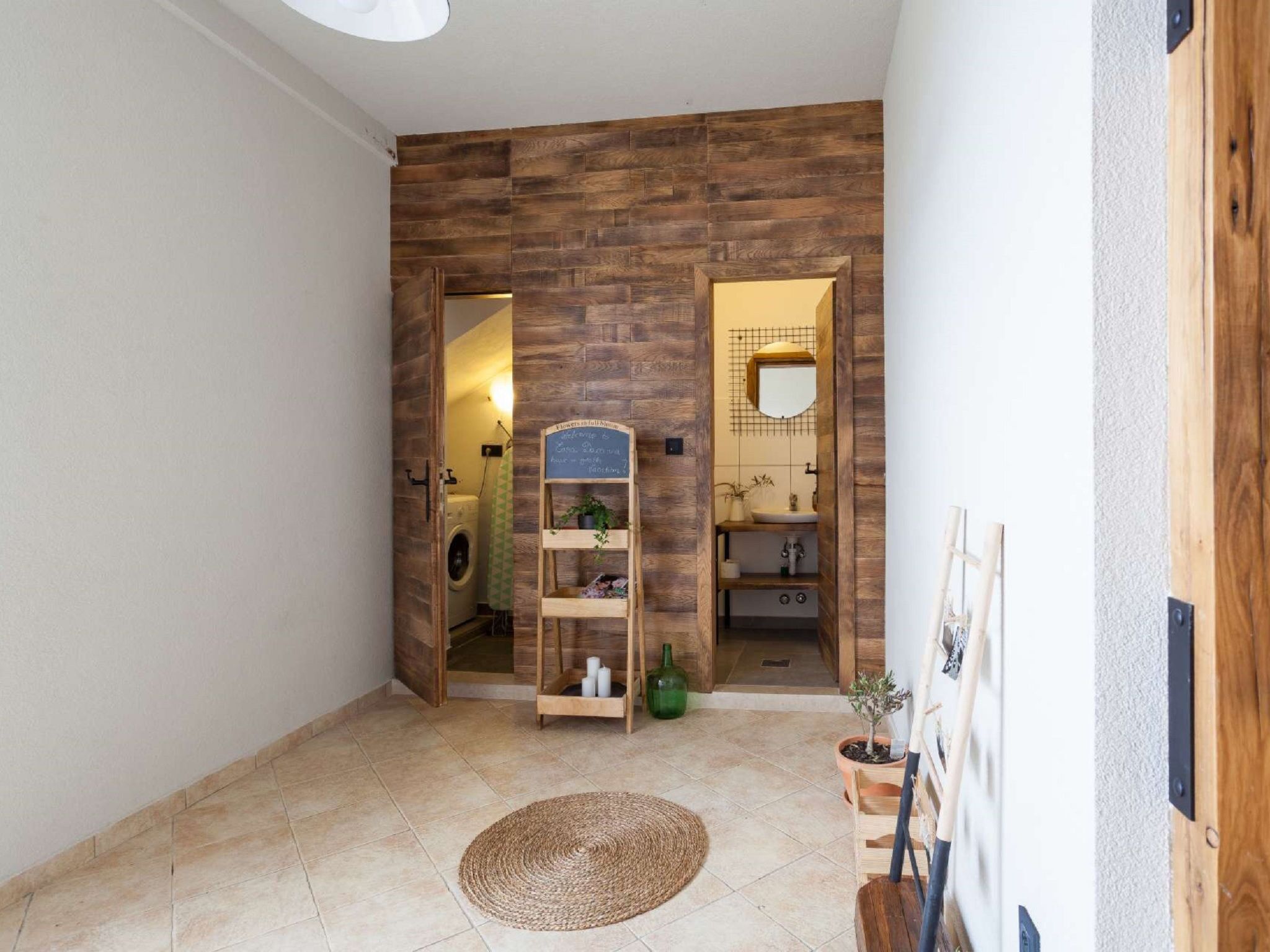 A hallway with a wooden wall, a laundry area, and a small shelf with items.