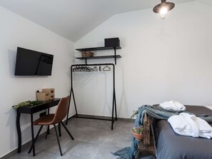 A compact bedroom with a bed, a desk, a chair, a TV, and a hanging clothes rack. - Villa Royal with heated pool by Interhome (Biograd na Moru)