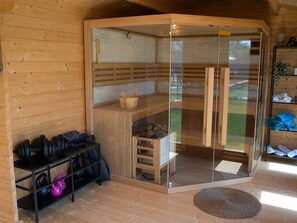 A wooden cabin with a glass-enclosed sauna, a wooden bench, a shelf with towels, and a small table with gym equipment. - Villa Royal with heated pool by Interhome (Biograd na Moru)