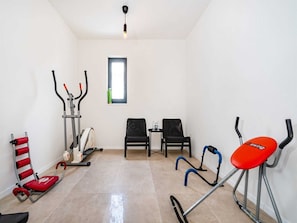 A room with a stationary bike, a rowing machine, and two chairs. - Villa Magale with a pool by Interhome (Biograd na Moru)