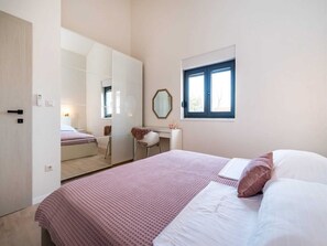 A bedroom with a bed, a dresser, a mirror, and a window. - Villa Magale with a pool by Interhome (Biograd na Moru)