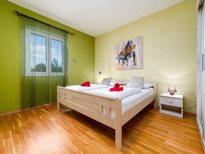 Un dormitorio con cama, mesita de noche y un cuadro en la pared.