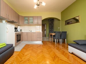Eine moderne Küche mit Holzschränken, einem Essbereich mit Tisch und Stühlen sowie einem Holzboden mit Fischgrätmuster.