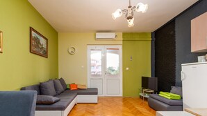 Ein modernes Wohnzimmer mit einer Couch, einem Esstisch und einer Küchenzeile mit einem Kühlschrank.