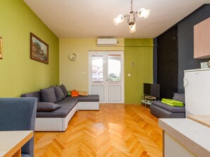 Ein modernes Wohnzimmer mit einer Couch, einem Esstisch und einer Küchenzeile mit einem Kühlschrank.