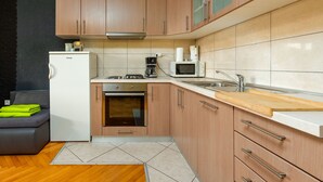 Eine kompakte Küche mit Holzausstattung, einem Einbauofen, einer Mikrowelle und einer Kaffeemaschine.