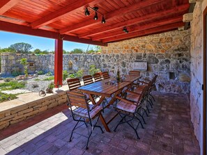 An outdoor patio with a stone wall, wooden table, and chairs. - Villa Jacassa with heated pool and jacuzzi by Interhome (Biograd na Moru)