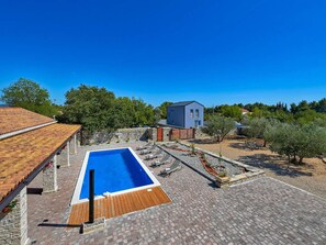 A rectangular swimming pool with a wooden deck, surrounded by a stone patio. - Villa Jacassa with heated pool and jacuzzi by Interhome (Biograd na Moru)