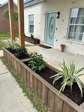 A residential building with a brick facade, a blue door, and a garden with raised beds. - Coastal charm Retreat : Bay and Beach nearby (Freeport)
