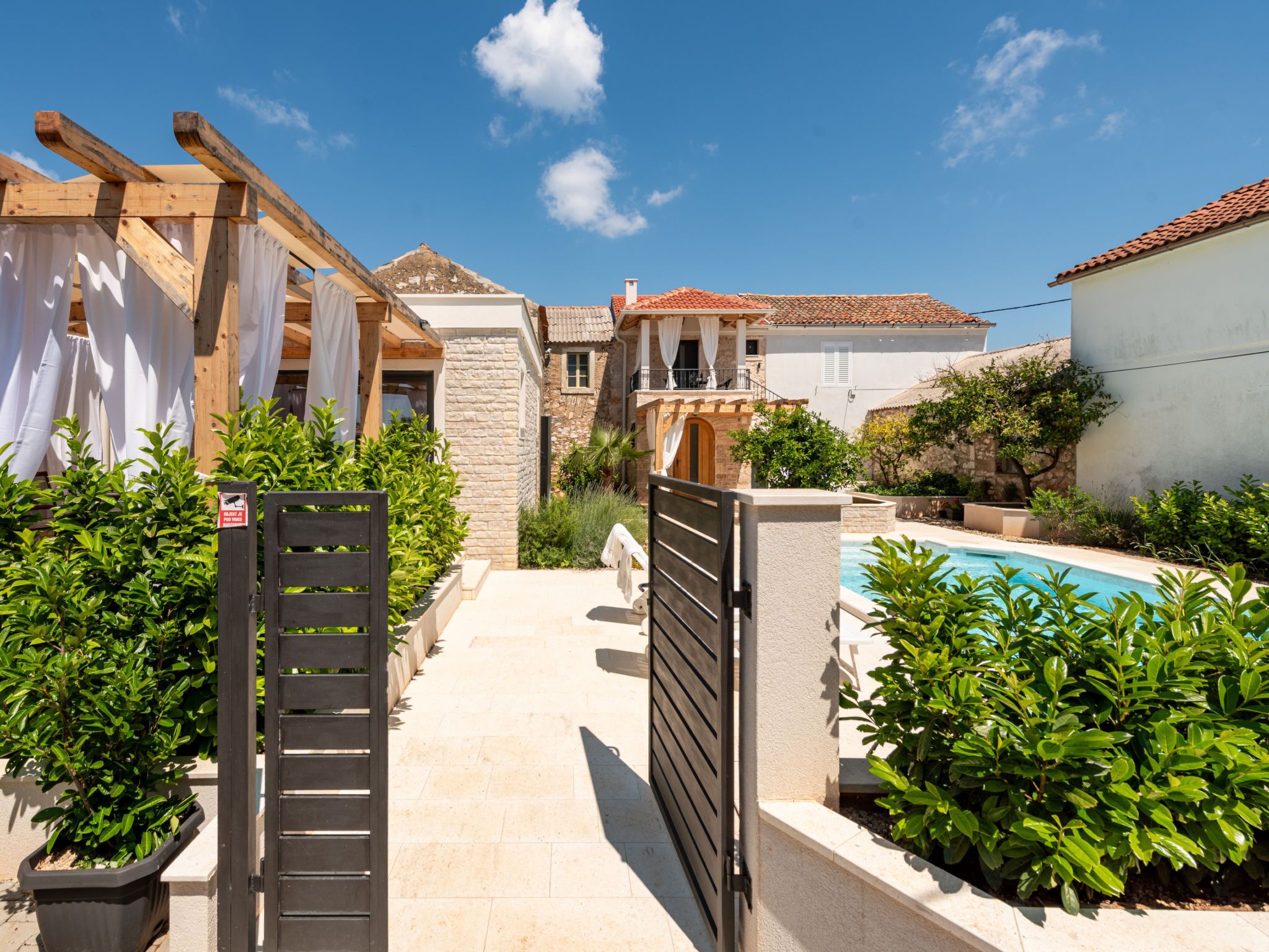 Une cour avec une piscine, des murs en pierre et une pergola en bois.