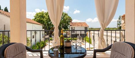 A balcony with two chairs, a table, and a bottle of wine.