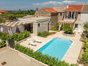 Ein Wohnhaus mit Swimmingpool, Sitzgelegenheiten im Freien und einem Garten.