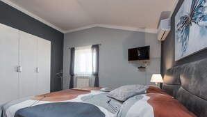 A bedroom with a bed, a TV mounted on the wall, and a painting above the bed. - Vacation home  by Interhome (Donje Rastane)