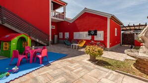 A red building with a balcony, a play area with a slide, and a fountain. - Vacation home  by Interhome (Donje Rastane)