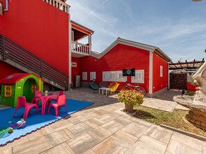 A red building with a balcony, a play area with a slide, and a fountain. - Vacation home  by Interhome (Donje Rastane)