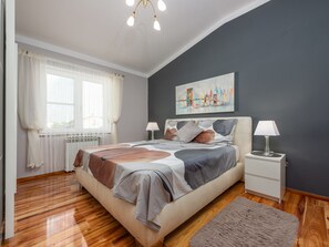 A bedroom with a bed, bedside tables, a window with curtains, a painting on the wall, and a rug on the floor. - Xxxl Villa Ancora with heated pool by Interhome (Donje Rastane)