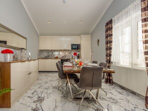 A modern kitchen with marble countertops, a dining area with a glass table, and a view of the outdoors through large windows. - Xxxl Villa Ancora with heated pool by Interhome (Donje Rastane)
