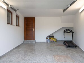 A clean, empty room with a wooden door, a treadmill, and a yellow hose on the floor. - Vacation home  by Interhome (Donje Rastane)