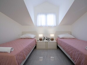 A twin bedroom with two beds, a skylight, and a nightstand with a bicycle. - Charming Villa Rea, 8+2 with heated pool by Interhome (Donje Rastane)