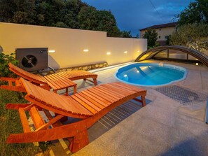 A swimming pool with wooden loungers, a stone wall, and a fan. - Charming Villa Rea, 8+2 with heated pool by Interhome (Donje Rastane)