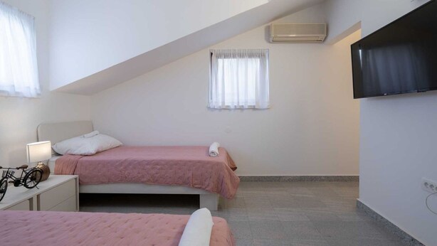 Ein Schlafzimmer mit zwei Betten, einem Fernseher und einem Fenster mit Vorhängen.