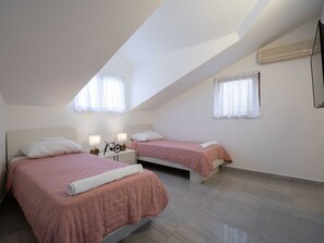 A bedroom with two beds, a nightstand, a bicycle, and a window with curtains. - Charming Villa Rea, 8+2 with heated pool by Interhome (Donje Rastane)